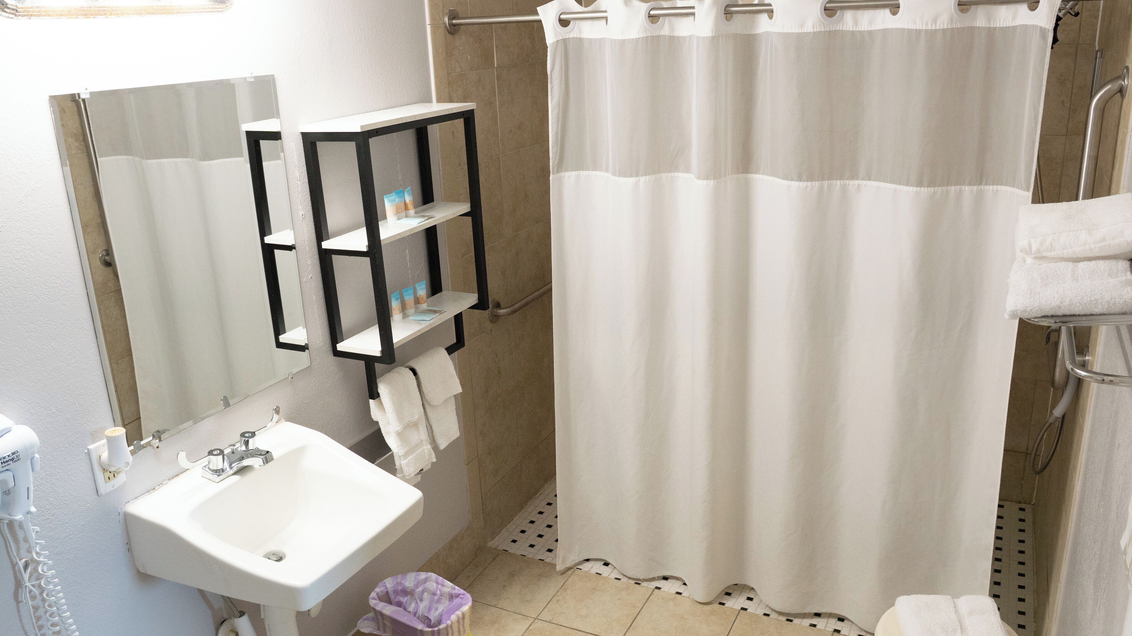 A bathroom with a white sink, a mirror, a towel rack, and a shower curtain.