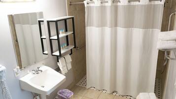 A bathroom with a white sink, a mirror, a towel rack, and a shower curtain.
