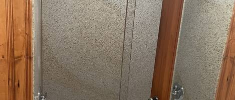 Un baño con bañera, paneles de madera y cabina de ducha.