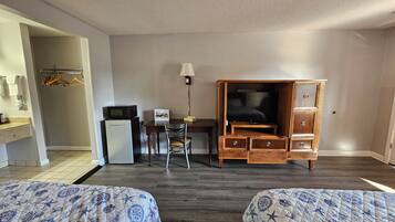A hotel room with two beds, a desk with a computer, a TV, and a wardrobe.