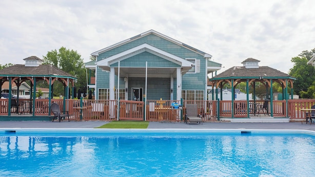 A pool area with a building that has a covered patio and a gazebo. - Atlantic Shores Inn and Suites (Chincoteague)