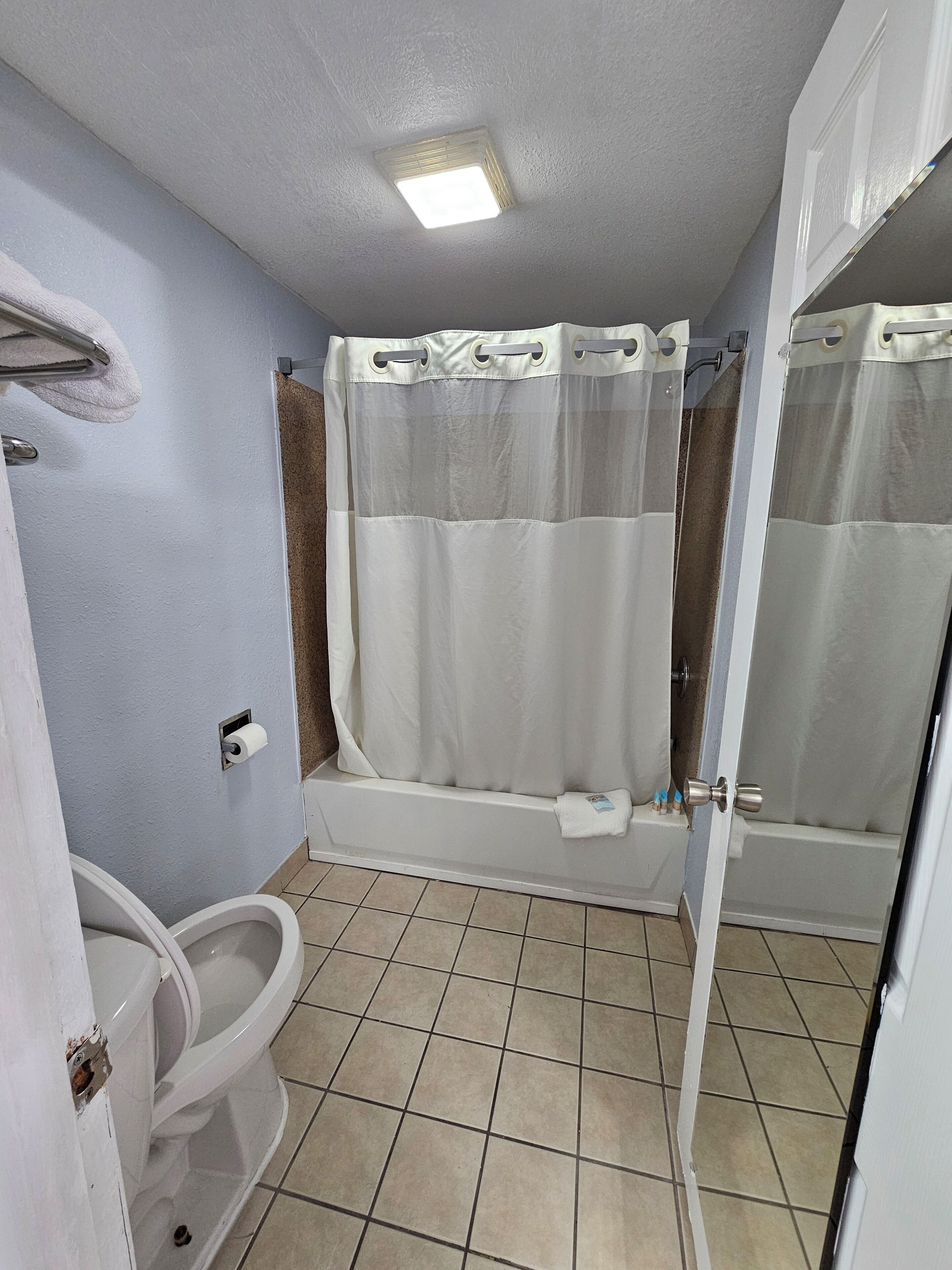 A bathroom with a bathtub, toilet, and shower curtain.
