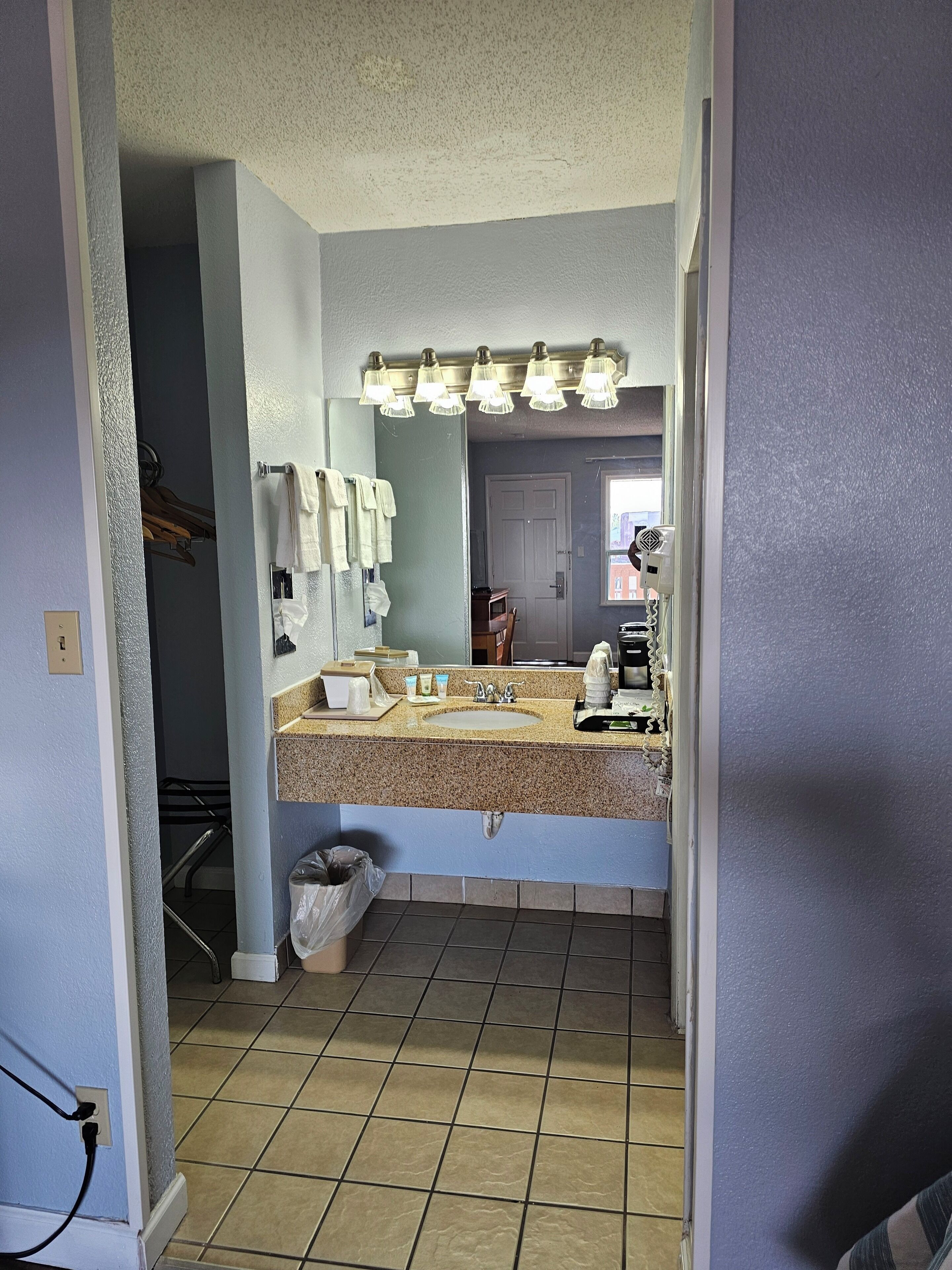 A bathroom with a granite countertop sink, a mirror, and a towel rack.