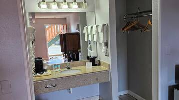 A bathroom with a sink, mirror, towel rack, and a view of the outside.