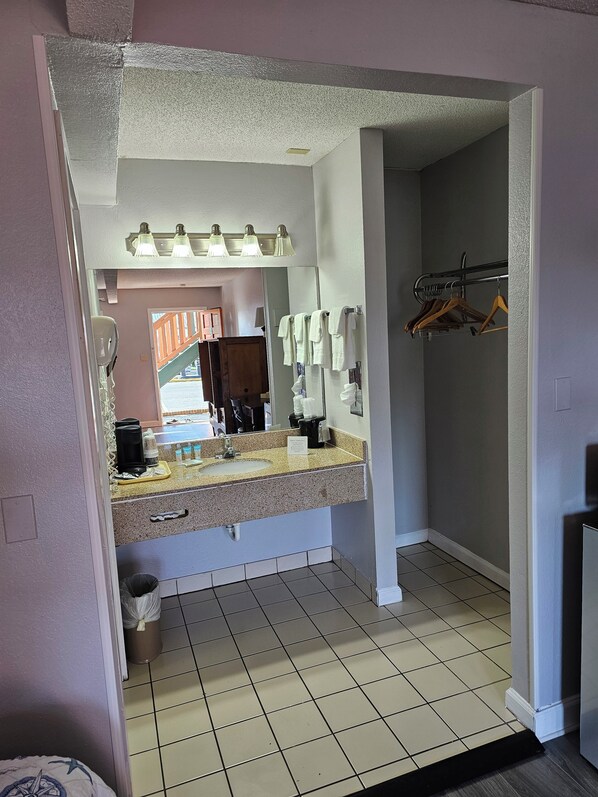 A bathroom with a sink, mirror, towel rack, and a view of the outside.