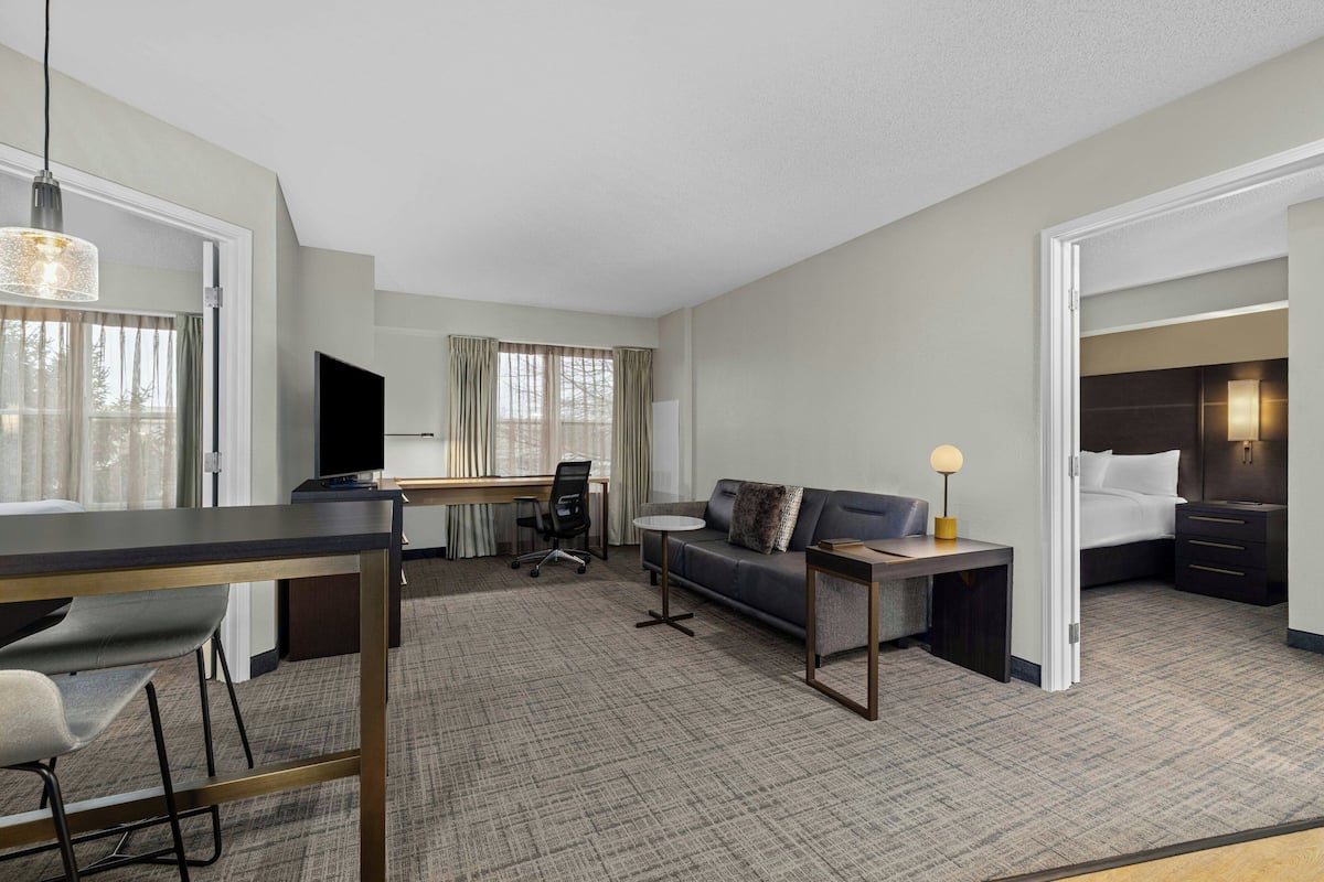 A hotel room with a desk, chair, sofa, and a bed.