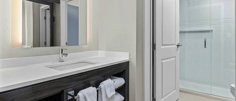 Une salle de bain moderne avec un meuble-lavabo blanc, un grand miroir et une cabine de douche en verre.