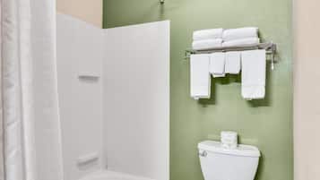 A bathroom with a white bathtub, a shower, and a toilet. There are towels hanging on a rack.