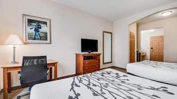 A hotel room with a bed, a desk with a chair, a television, and a painting on the wall.