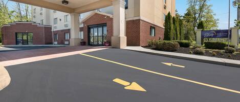 Entrada de un hotel con zona de estacionamiento techada, flechas direccionales indicativas y un letrero de Sleep Inn Suites.