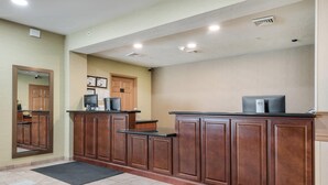 A reception area with wooden cabinets, a reception desk, a computer, and a mirror. - Sleep Inn & Suites Gettysburg (Gettysburg)