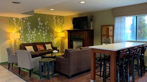 A modern living room with a sofa, chairs, a coffee table, and a dining area with a table and chairs. - Sleep Inn & Suites Gettysburg (Gettysburg)