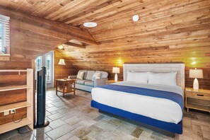 Una habitación con paneles de madera, una cama grande, un sofá, un televisor y una lámpara.