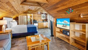 A cozy cabin with a wooden interior, a bed, a TV, and a kitchenette. - Eden House (Key West)