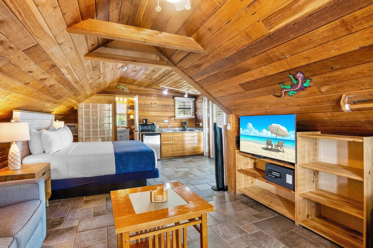Ein gemütliches Blockhaus mit Holzinnenraum, einem Bett, einem Fernseher und einer Küchenzeile.