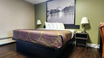 A hotel room with a bed, two bedside lamps, a nightstand, and a large framed picture on the wall.