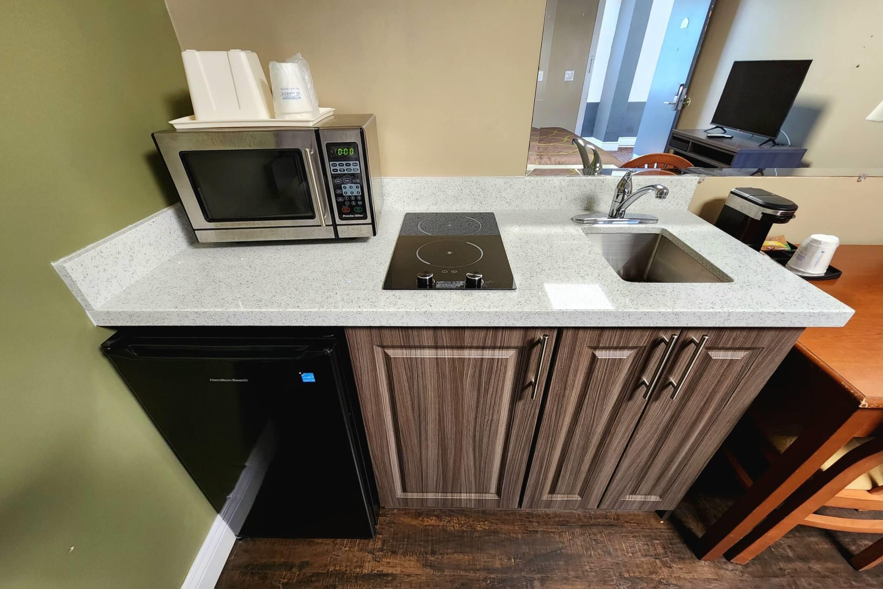 A compact kitchen with a built-in microwave, a stovetop, and a sink.