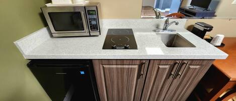 A compact kitchen with a built-in microwave, a stovetop, and a sink.