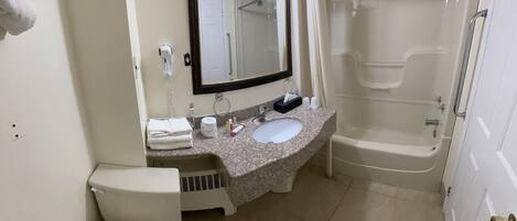 A bathroom with a toilet, sink, mirror, and shower.