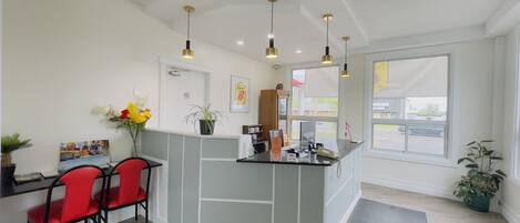 A reception area with a counter, a desk with chairs, and a large window providing a view of the outside.
