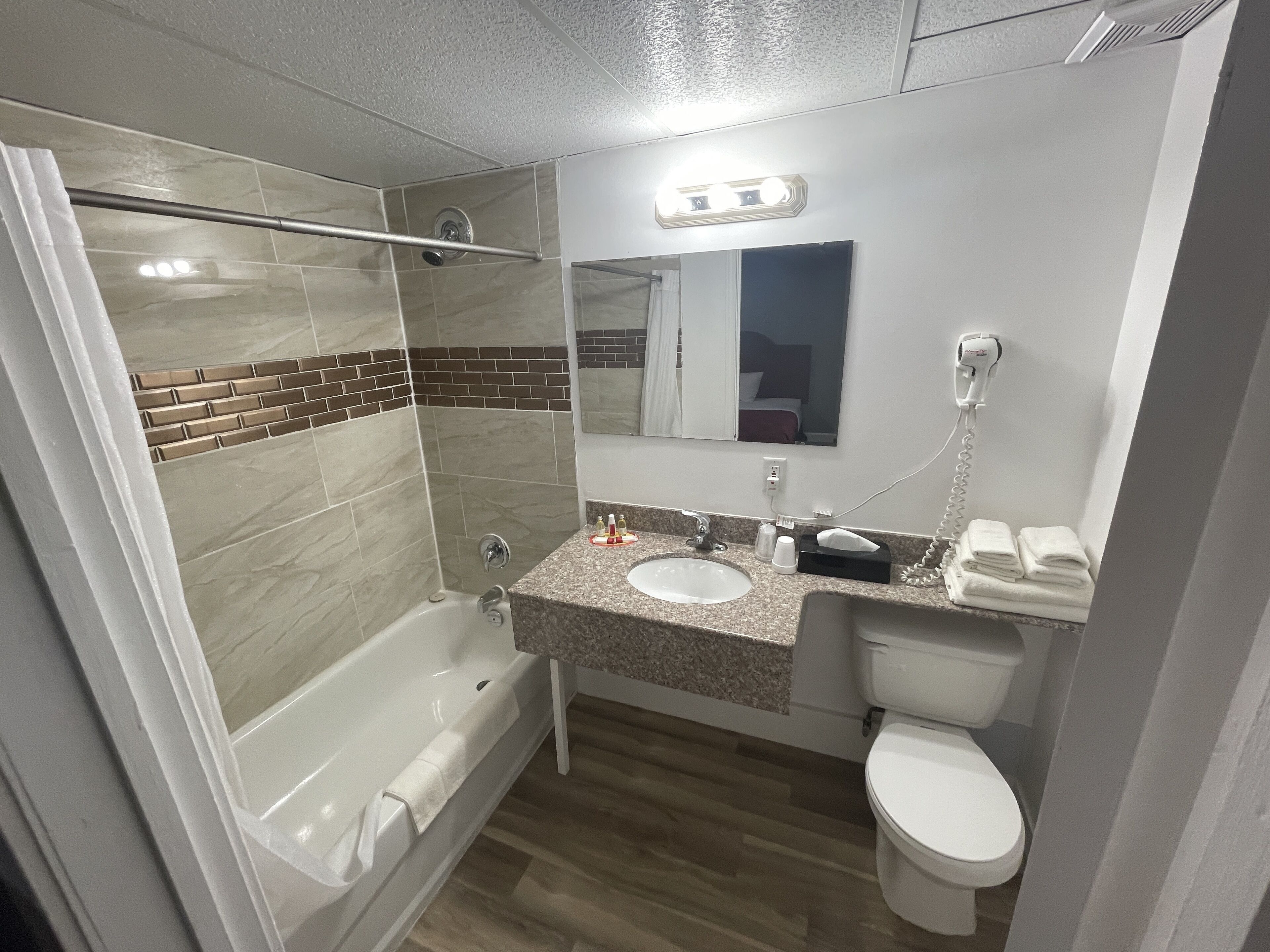 A bathroom with a bathtub, a sink, a toilet, and a shower area.