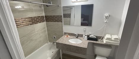 A bathroom with a bathtub, a sink, a toilet, and a shower area.
