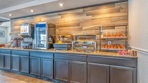 Zona de bufé con estación de café, vitrina refrigerada y diversas opciones de alimentos.