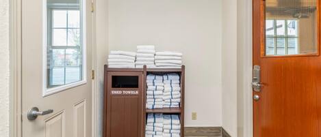 A hallway with a wooden door labeled "EXIT" and a rack labeled "USED TOWELS" filled with folded towels.