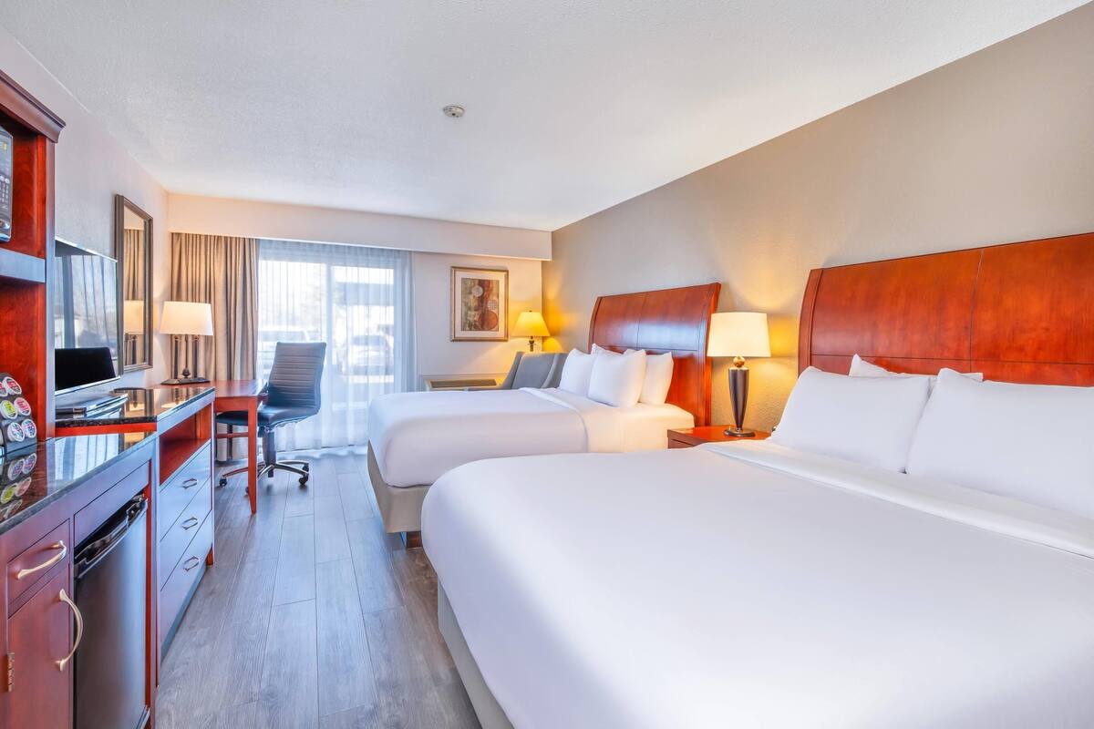 Een hotelkamer met twee bedden, een bureau, een stoel en een televisie.