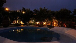 A nighttime scene with a swimming pool surrounded by snow, trees, and illuminated by streetlights. - Hotel Casas Alberto (San Miguel de Abona)