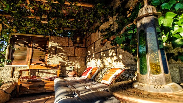 A cozy outdoor seating area with a cushioned bench, a wooden table, and a decorative lantern. - Hotel Casas Alberto (San Miguel de Abona)