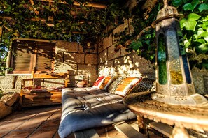 A cozy outdoor seating area with a cushioned bench, a wooden table, and a decorative lantern. - Hotel Casas Alberto (San Miguel de Abona)