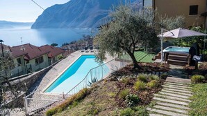 A swimming pool with a mountain view, a patio area with a hot tub, and a staircase leading to the pool. - Hotel Ristorante Miranda (Riva di Solto)