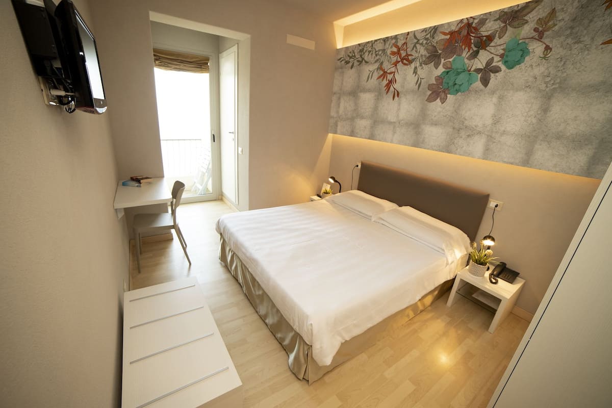 A bedroom with a bed, bedside tables, a desk, and a chair.