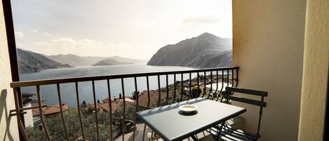 Un balcón con una mesa y sillas, con vistas a un lago y montañas.
