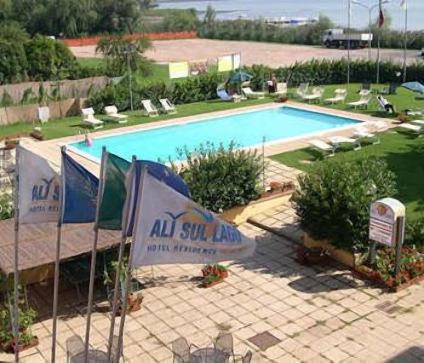 A swimming pool with lounge chairs and a sign for 'ALISUL LAND HOTEL & RESORT'.