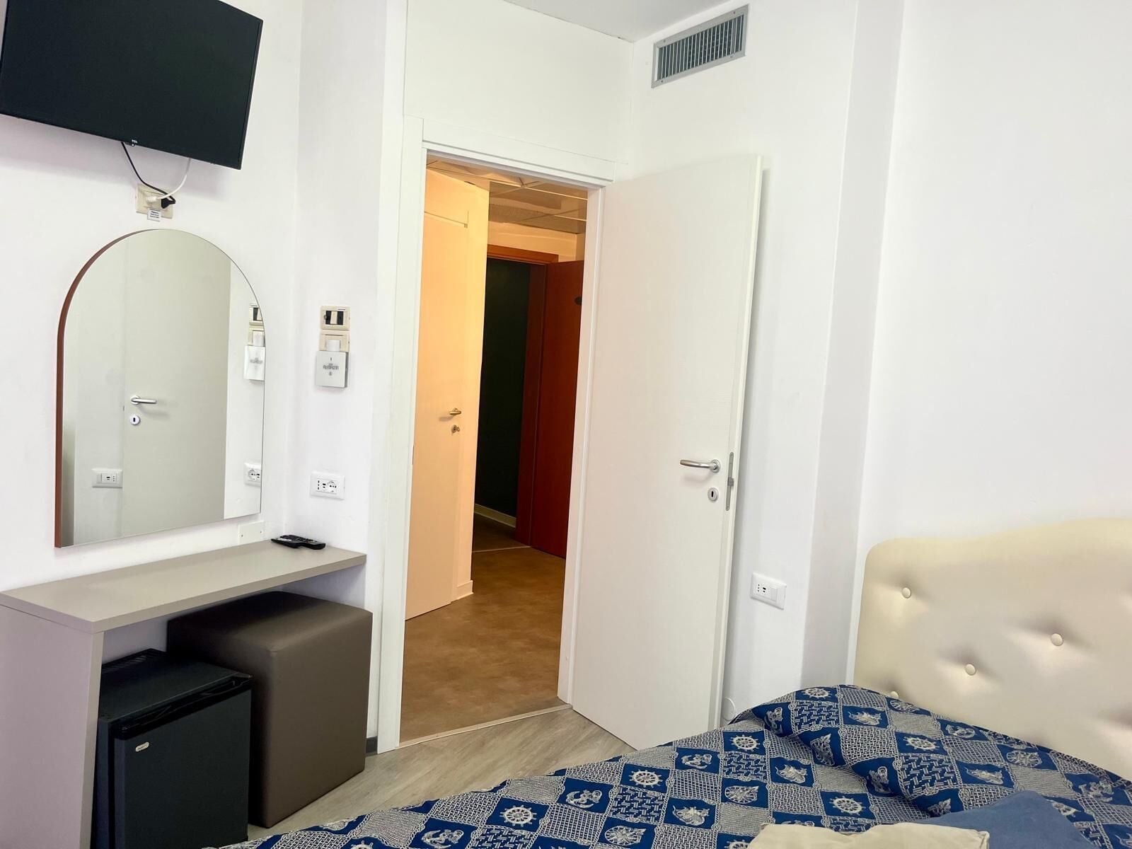 Ein Schlafzimmer mit Bett, Schreibtisch, Fernseher und Kleiderschrank.