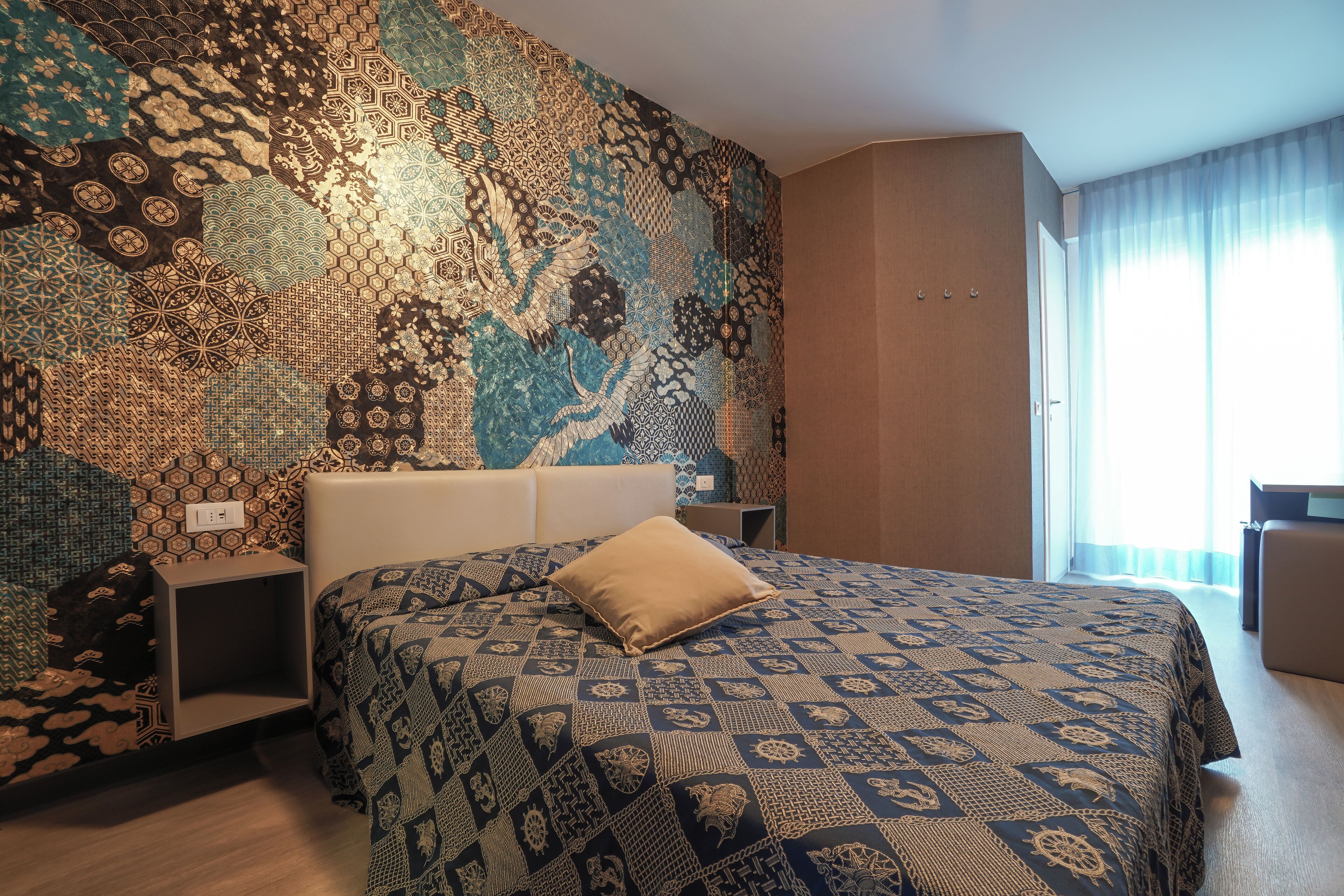 Una habitación de hotel con un papel tapiz estampado, una cama con colcha estampada, una mesita de noche y un escritorio.