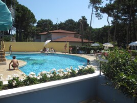 Una piscina al aire libre, sombrillas, sillones reclinables de piscina