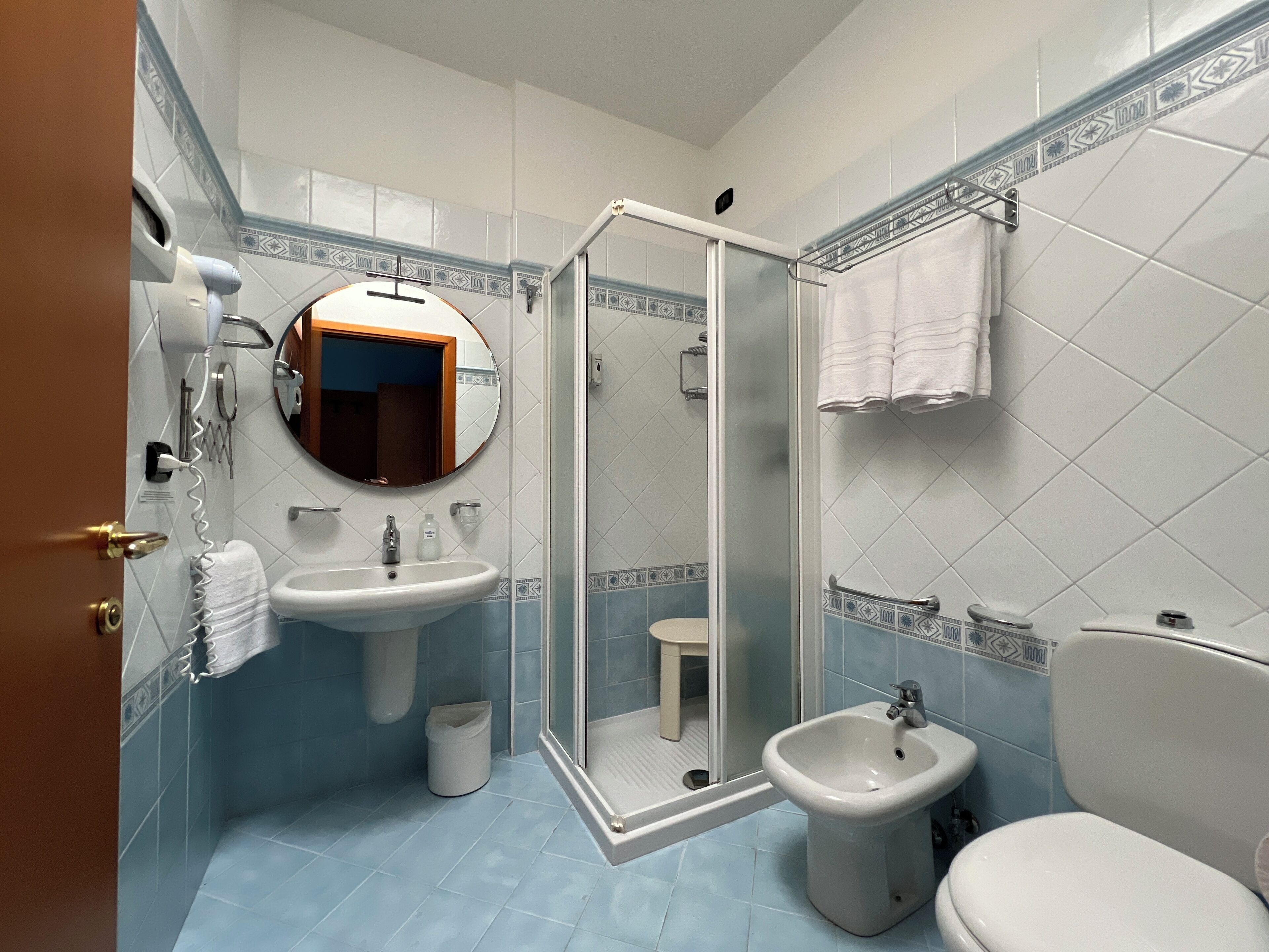 Un baño con lavamanos, bidé, inodoro y ducha con mampara de vidrio.
