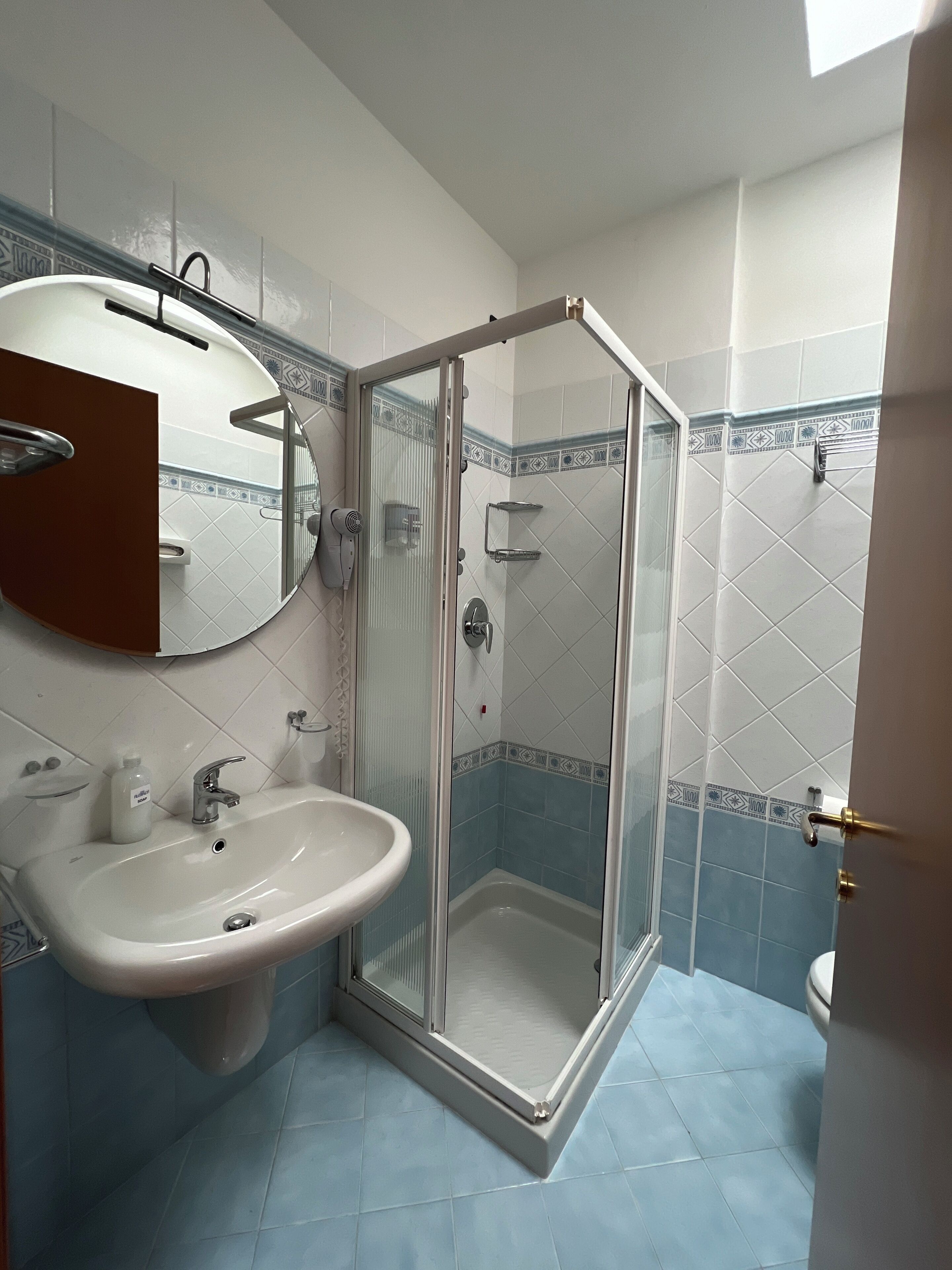 A bathroom with a glass-enclosed shower, a sink, and a mirror.