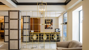 A lobby with a marble floor, a sofa, a reception desk with a gold frame, and a chandelier. - Hotel YIT Casablanca (Granada)