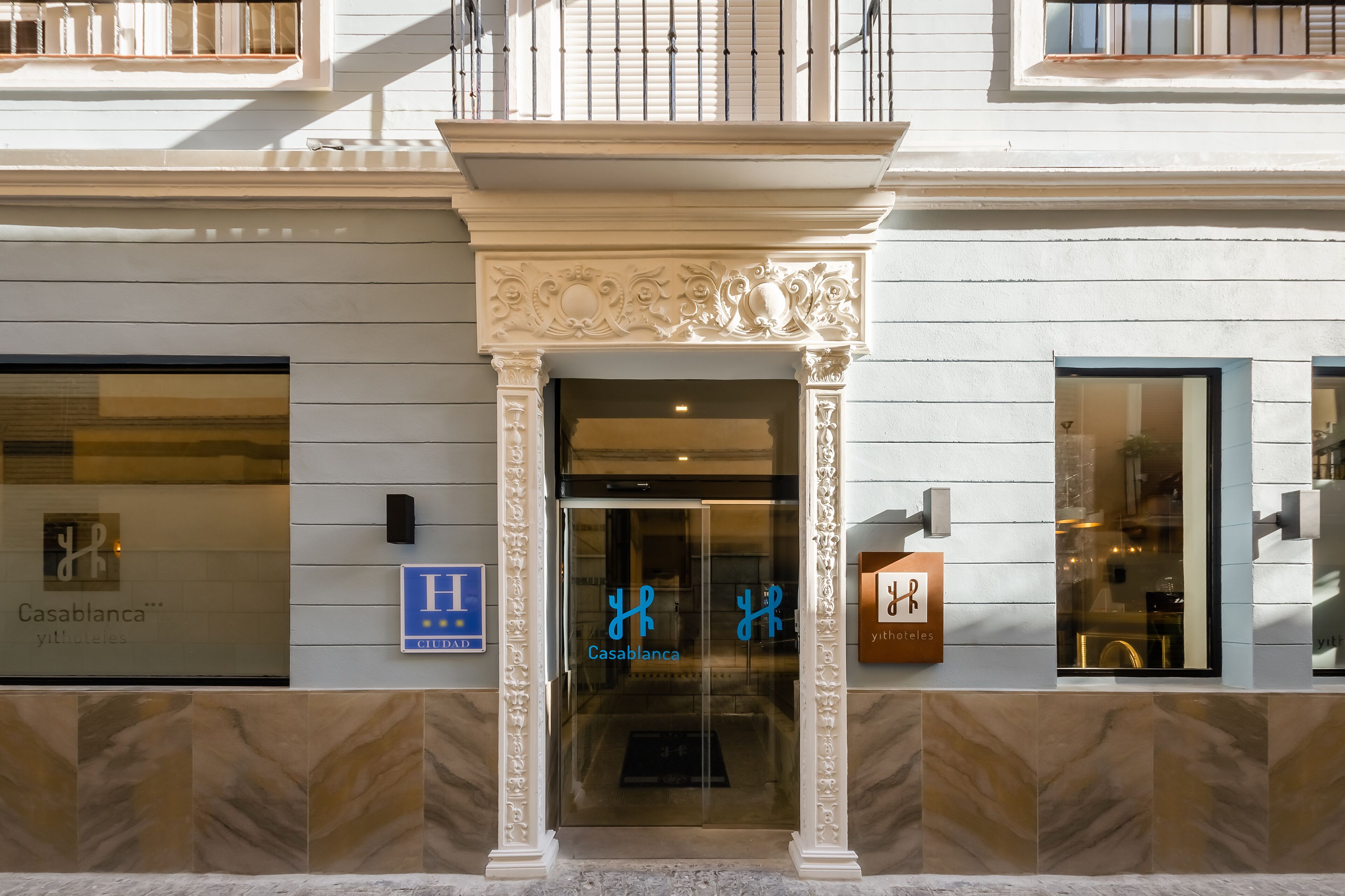 A hotel entrance with a glass door, a sign for 'Casablanca', and a 'H' sign indicating a hotel.