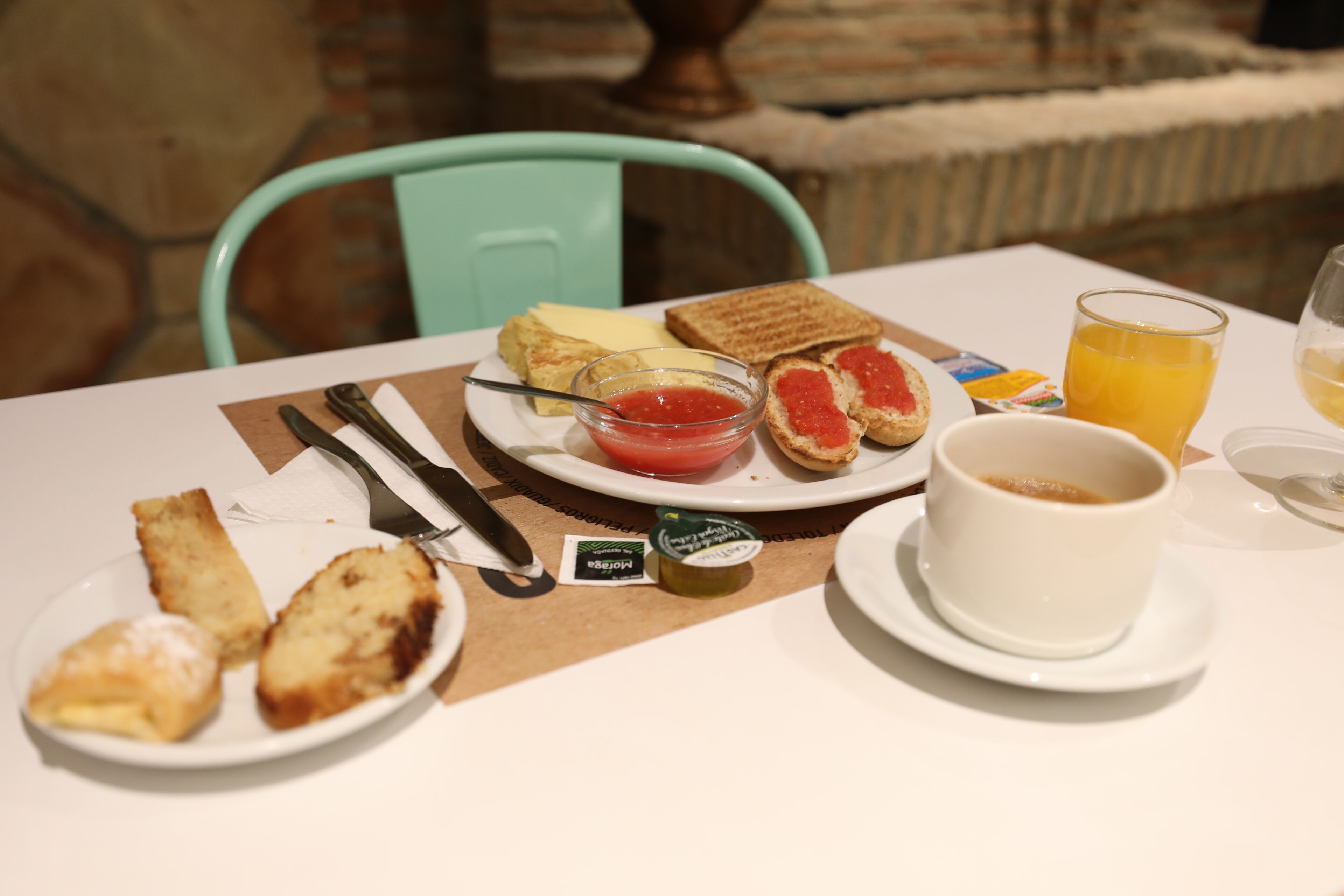 A breakfast table with toast, jam, butter, and a cup of coffee.