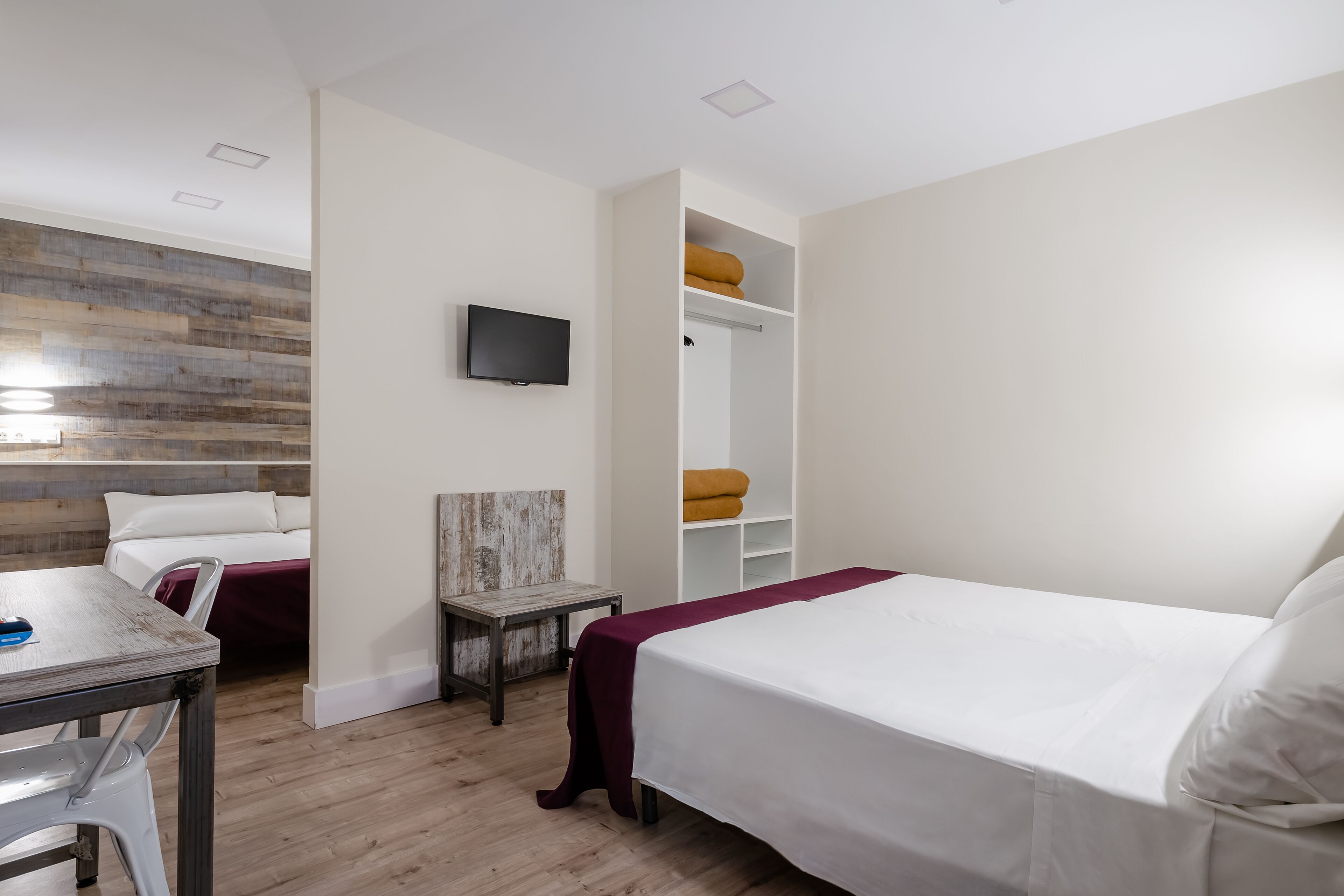 Una camera da letto con un letto, una scrivania, una sedia, una TV e un armadio.