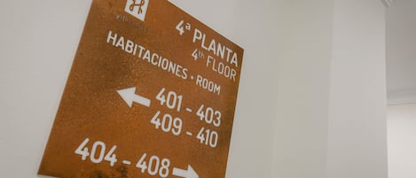 A sign indicating room numbers 401-403, 409-410, and 404-408 on the 4th floor of a hotel.