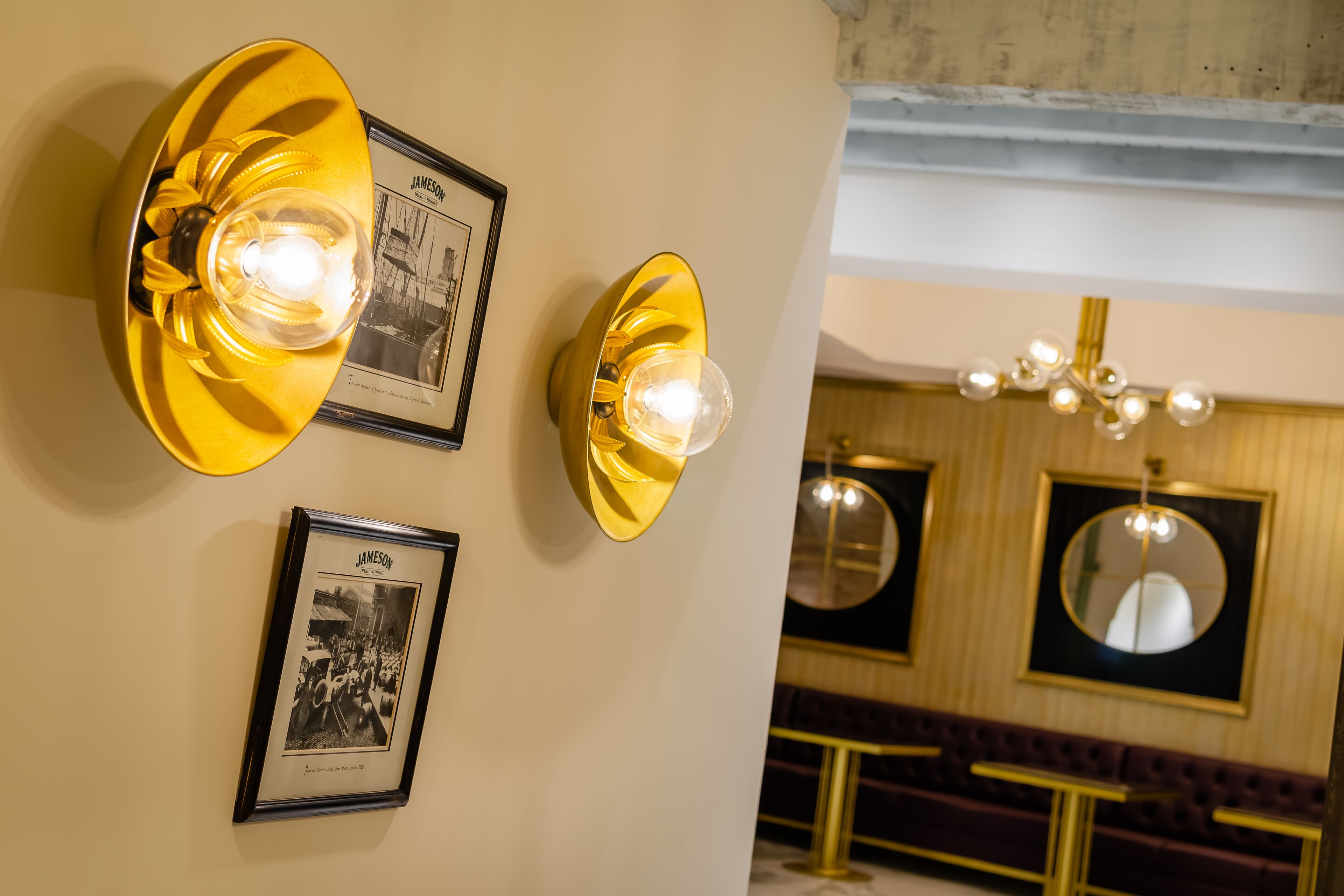 A wall-mounted light fixture with a clear bulb, a framed photograph, and a mirror.