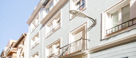 Un hôtel à plusieurs étages, doté d’une façade claire, de balcons et situé sur une rue pavée.