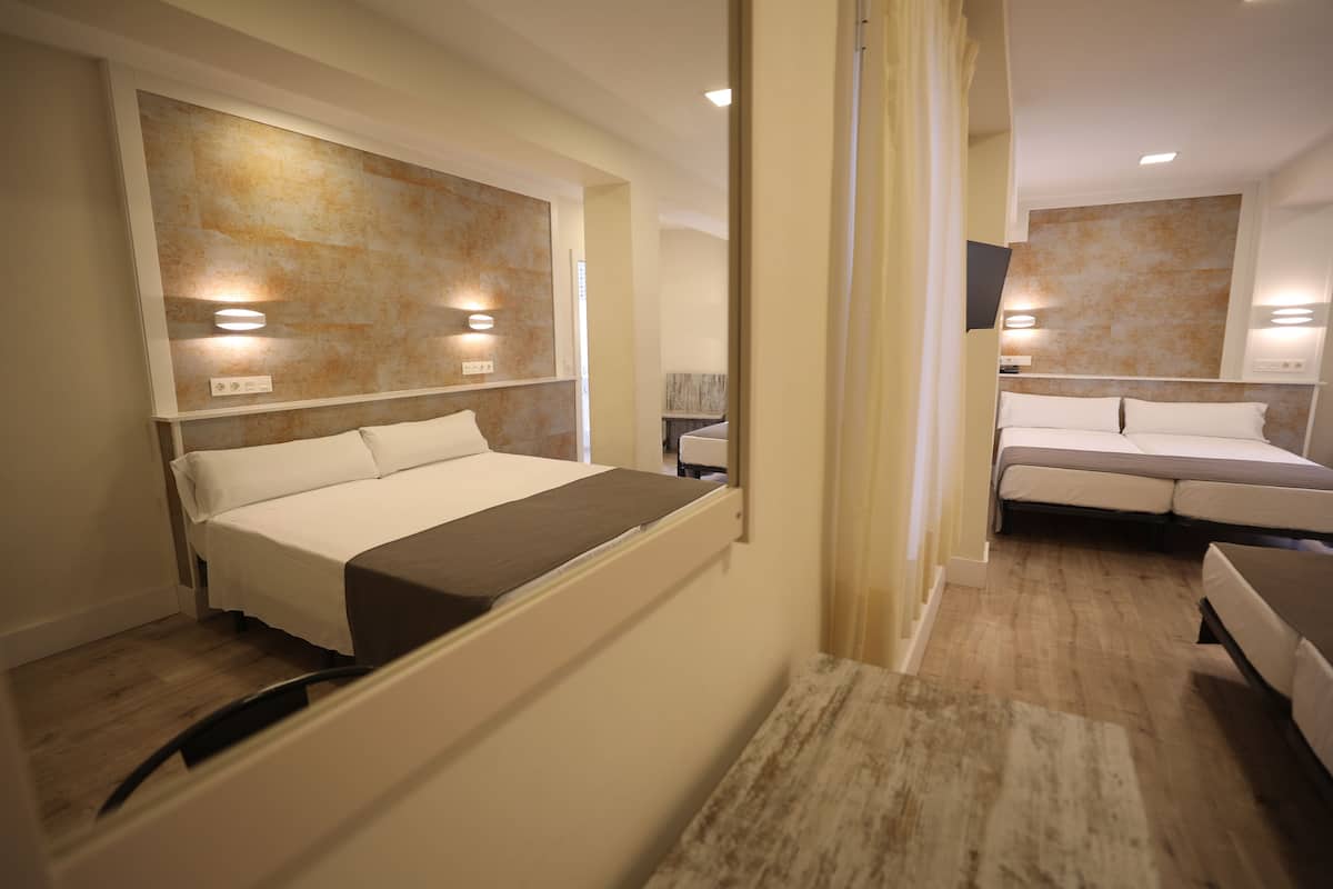 Una habitación de hotel con una cama, una mesita de noche y un espejo.