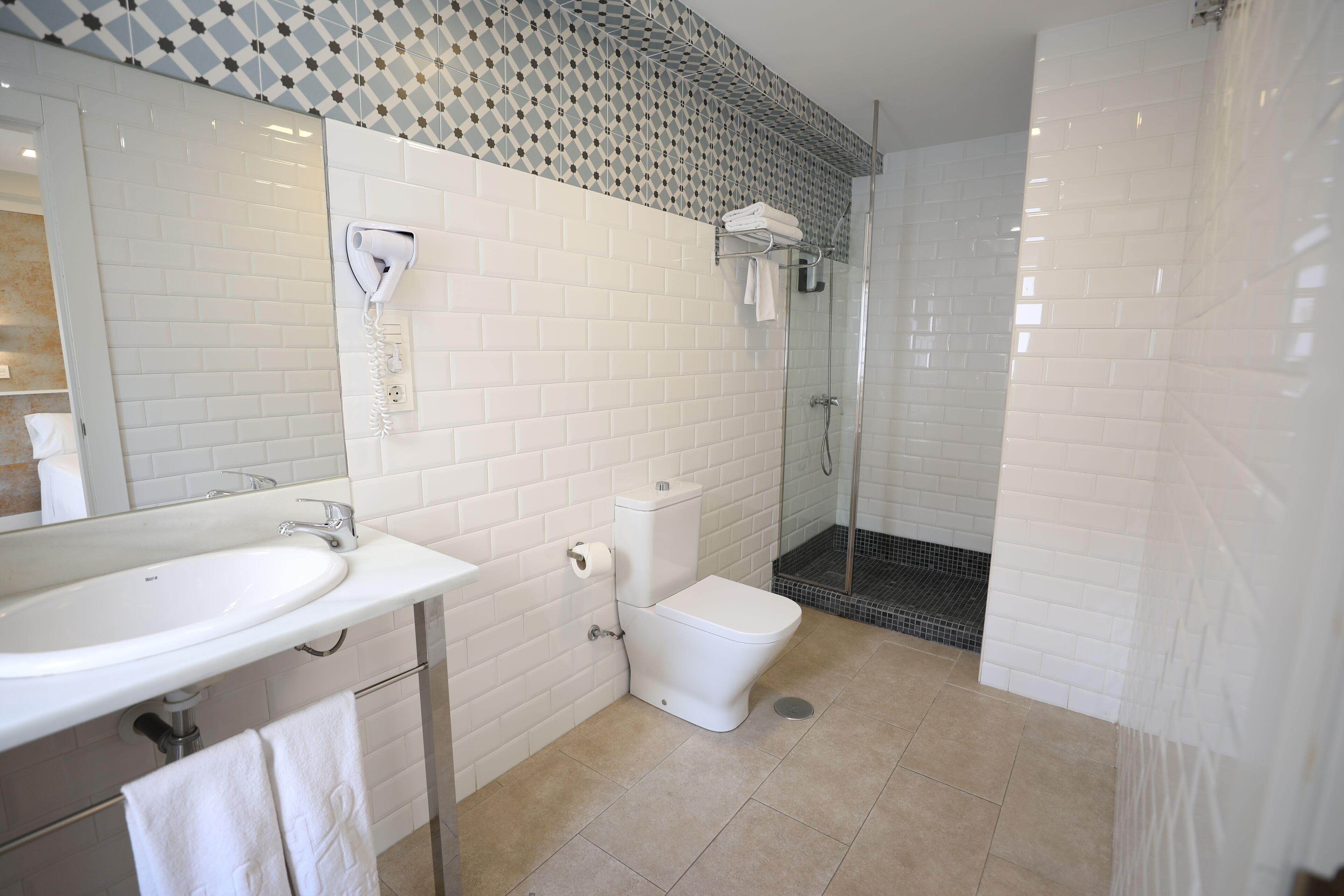 Un baño con lavamanos, inodoro y ducha blancos.